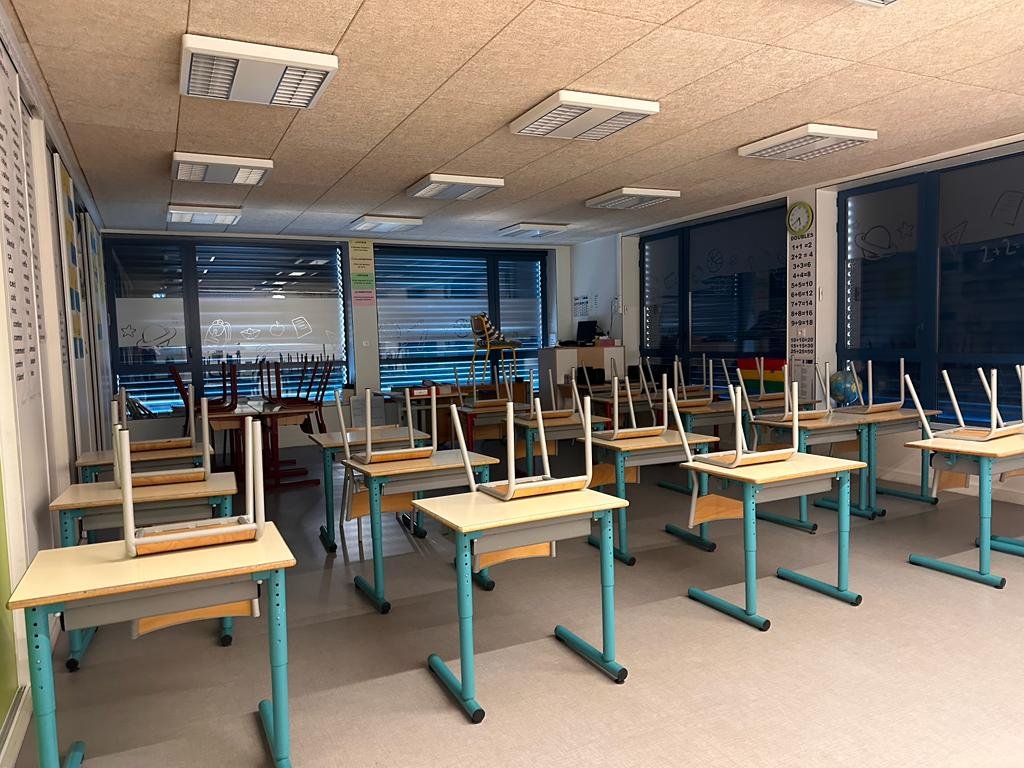 Photo d'une salle de classe avec chaises sur les bureaux